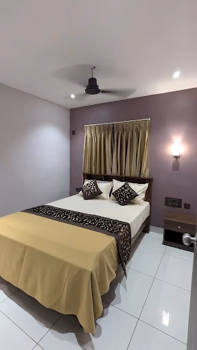 Amrut Inn Murudeshwar clean AC bedroom with modern purple decor and ceiling fan