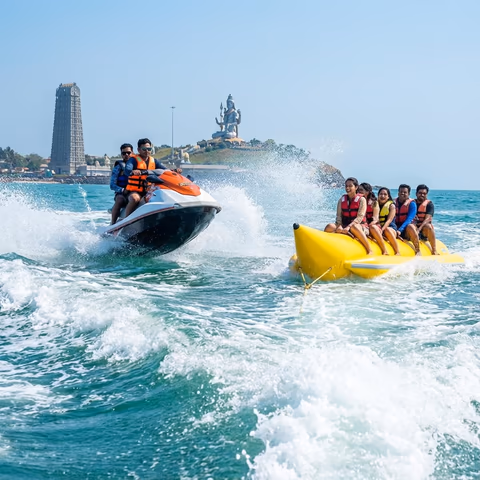 Tourists enjoying jet ski and banana boat ride at Murudeshwar beach with temple in background